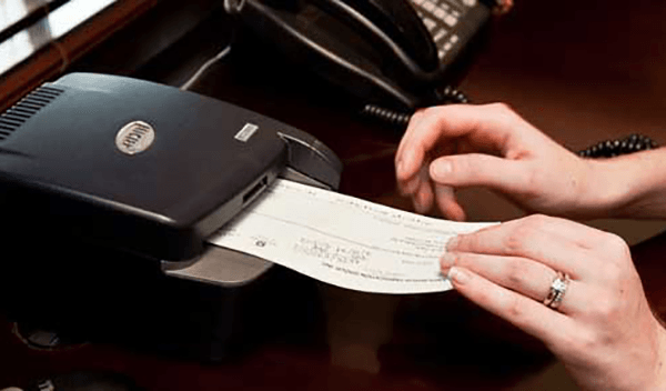 Hand holding a check and scanning it with a scanner machine